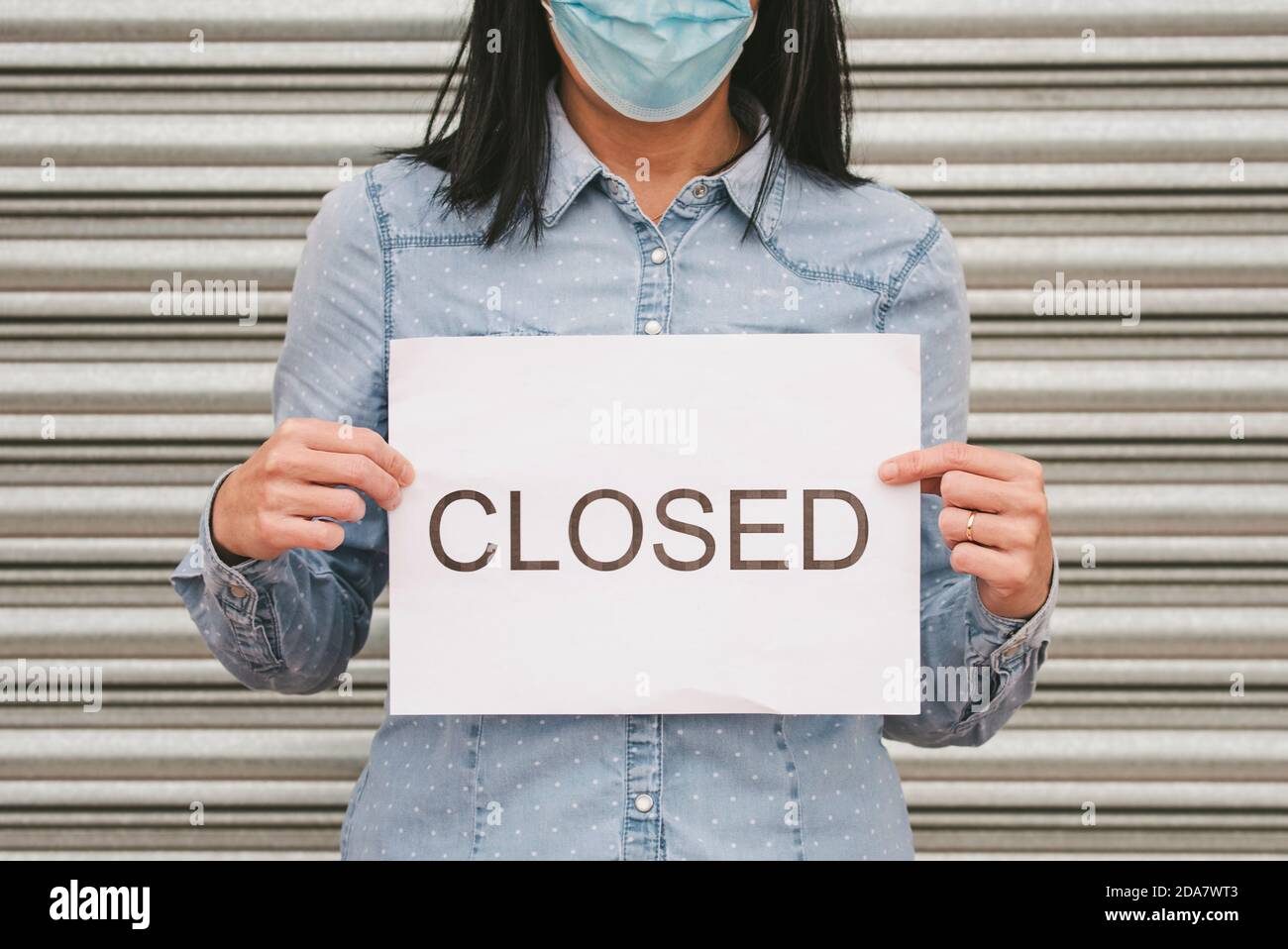 Coronavirus.Woman mit medizinischen Gesichtsmaske hält einen weißen Karton mit Der Text Closed.Store Closing aufgrund des coronavirus.Selective Fokus Stockfoto