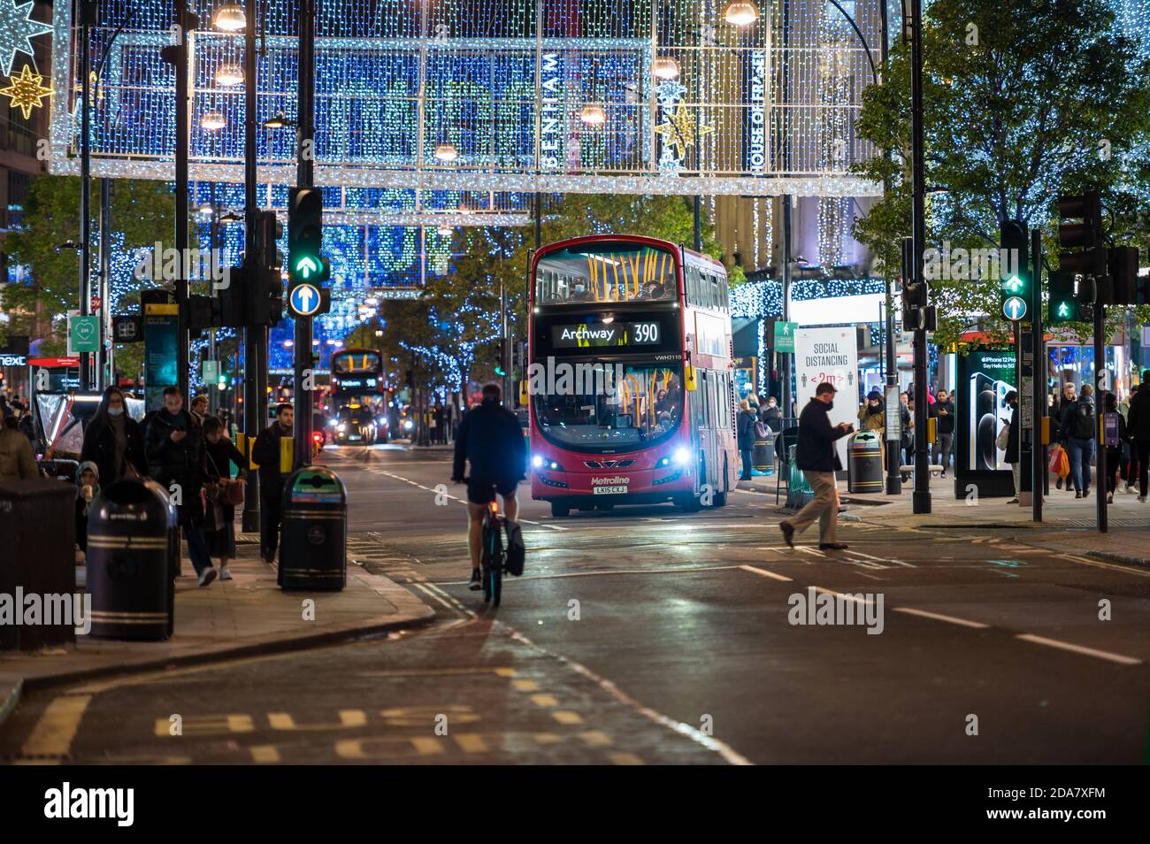 LONDON - 3. NOVEMBER 2020: Red London Double Decker Bus fährt von der Bushaltestelle auf der Oxford Street, die von Weihnachtslichtern beleuchtet wird Stockfoto