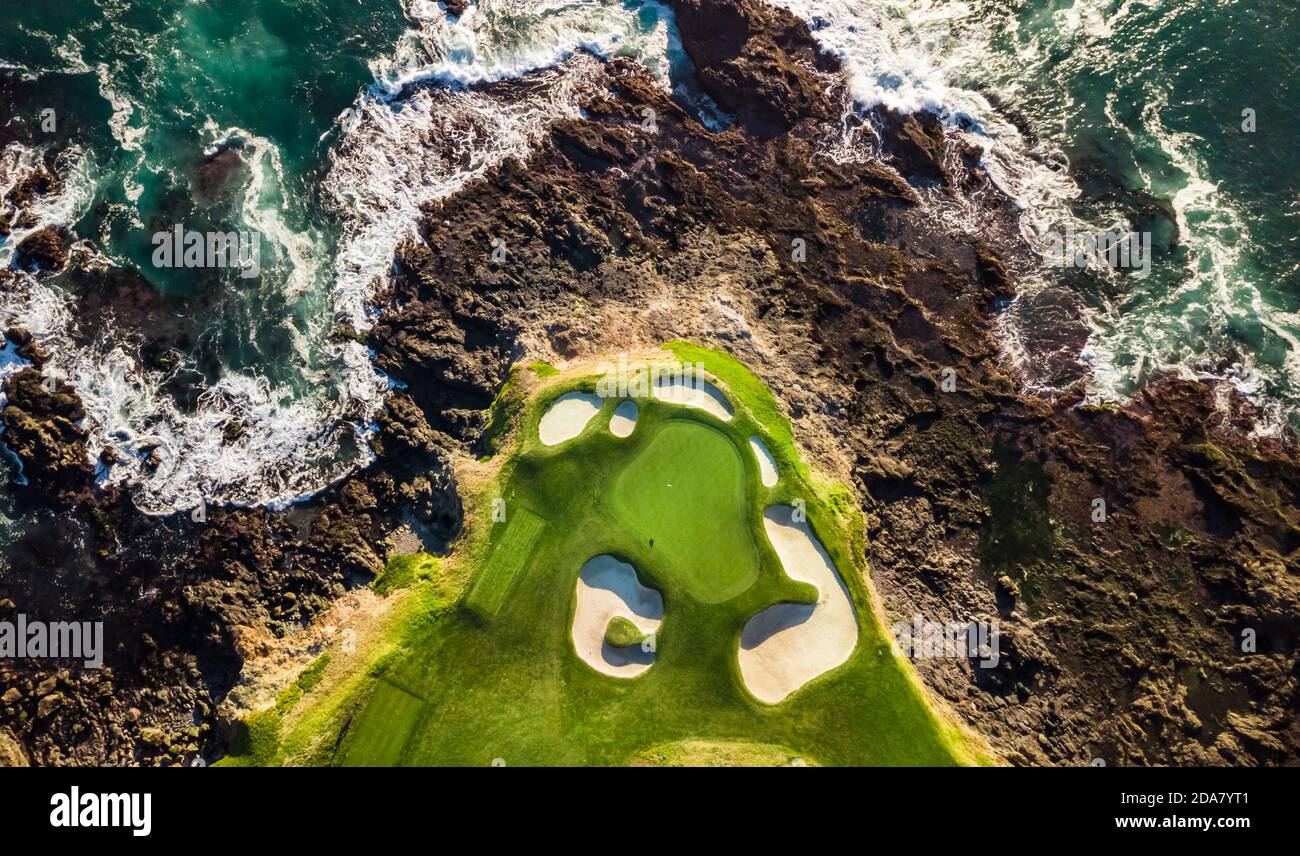 Drohne Blick auf den Kiesstrand Golfplatz neben Das Meer mit Wellen, die bei Ebbe auf die Felsen treffen In Monterey, Kalifornien Stockfoto