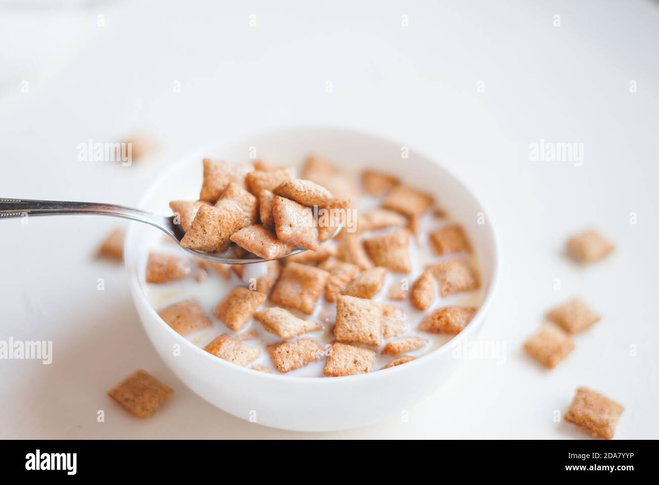 Trockene Frühstücksflocken mit Milch auf weißem Beton Hintergrund Stockfoto