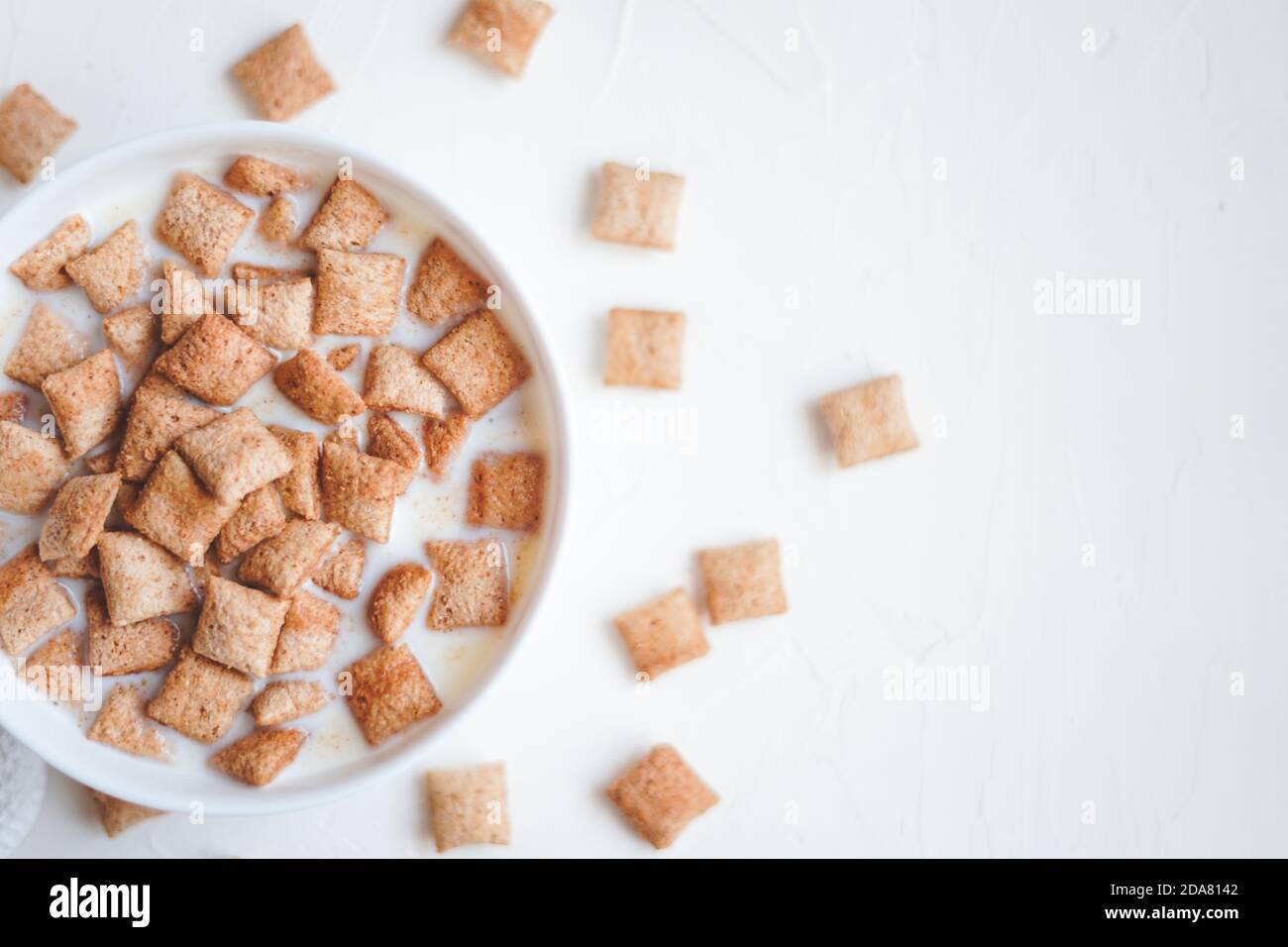 Trockene Frühstücksflocken mit Milch auf weißem Beton Hintergrund Stockfoto