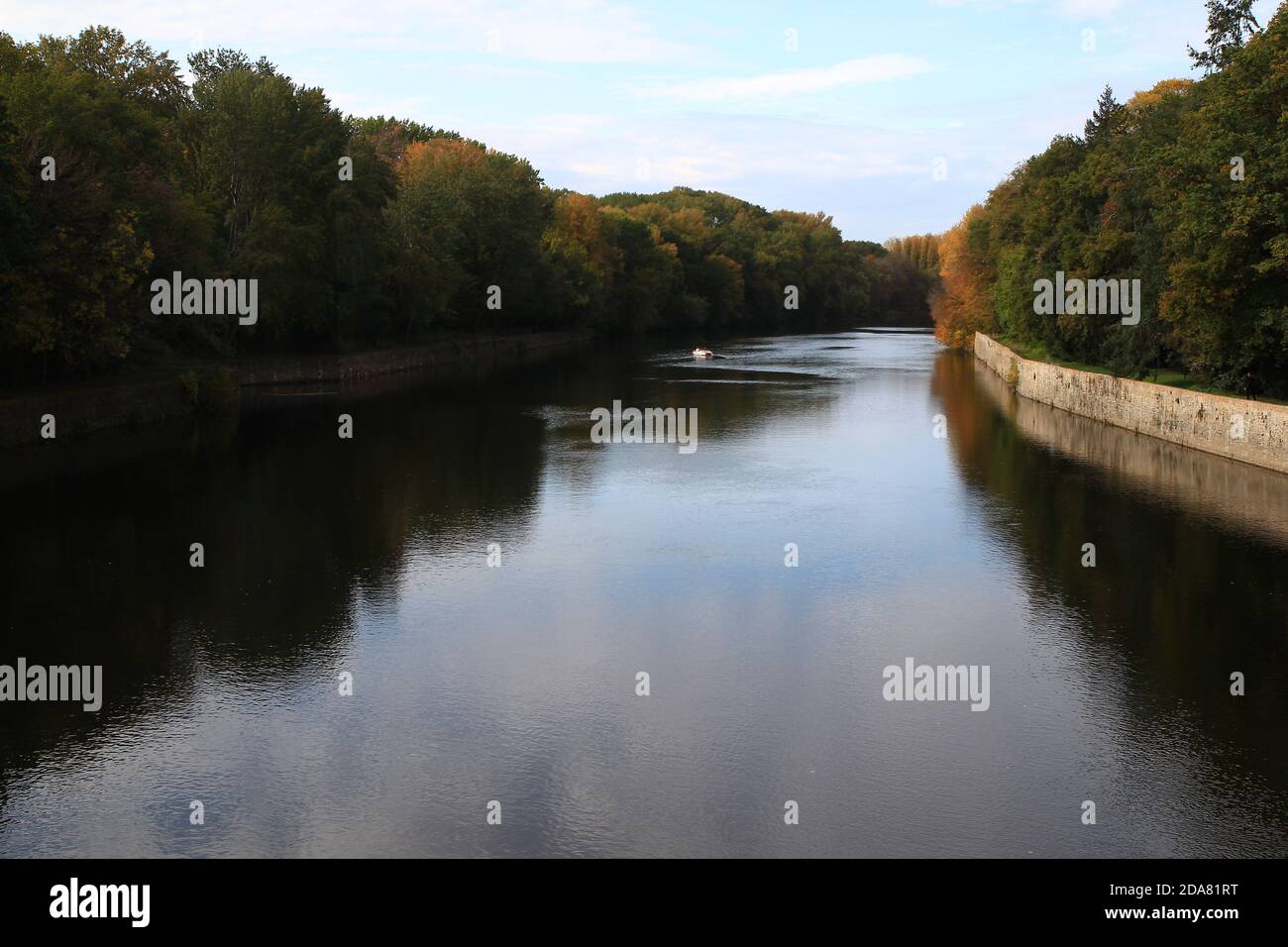 Im Herbst segelt ein kleines Boot friedlich auf dem Fluss Cher, gesäumt von hohen Bäumen (Loire - Frankreich) Stockfoto