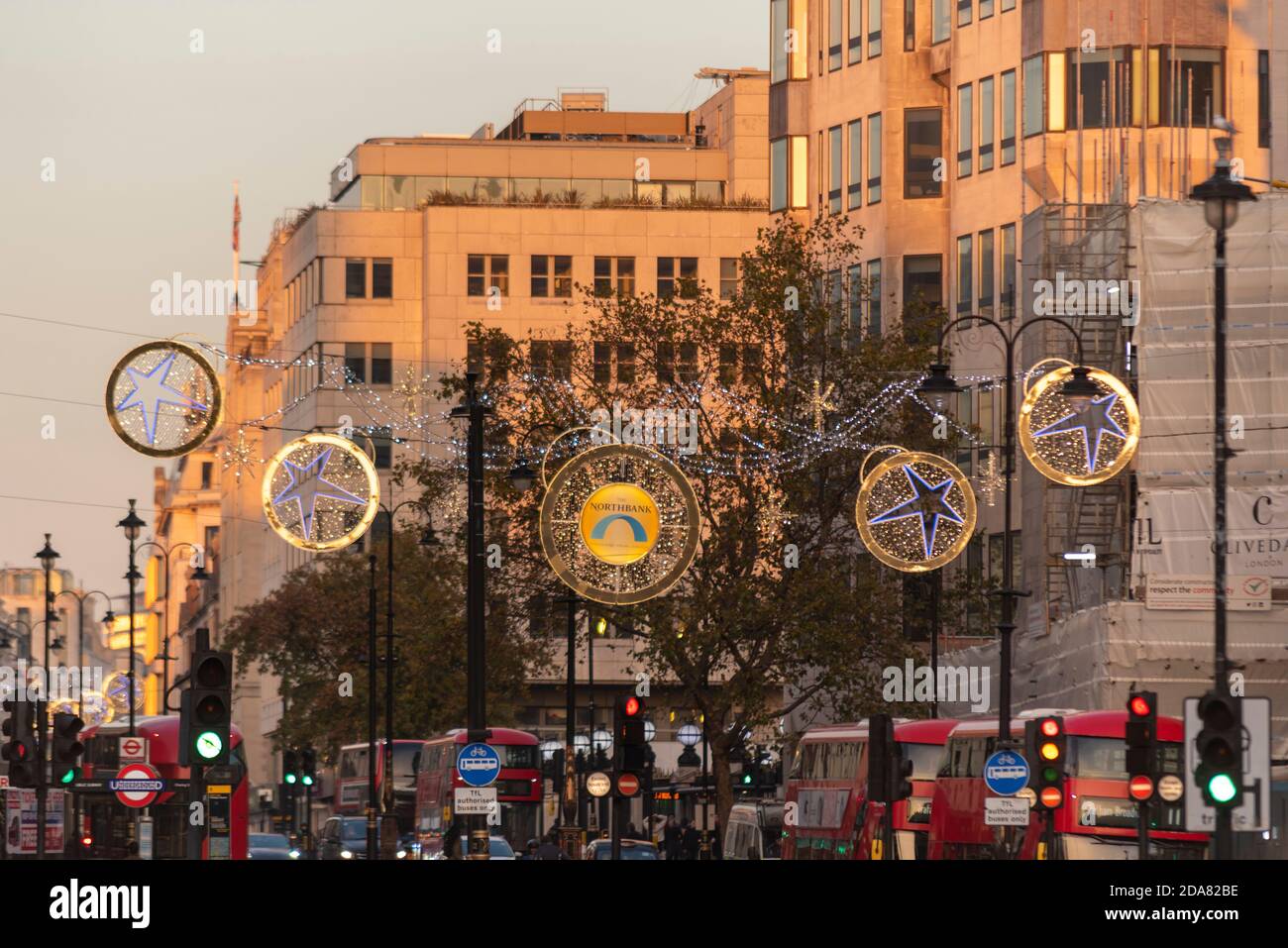 Weihnachtsbeleuchtung in The Strand, London, Großbritannien. Dämmerung Sonnenlicht mit Beleuchtung beleuchtet. Rote Londoner Busse. Besetzt während COVID 19 Sekunden gesperrt Stockfoto