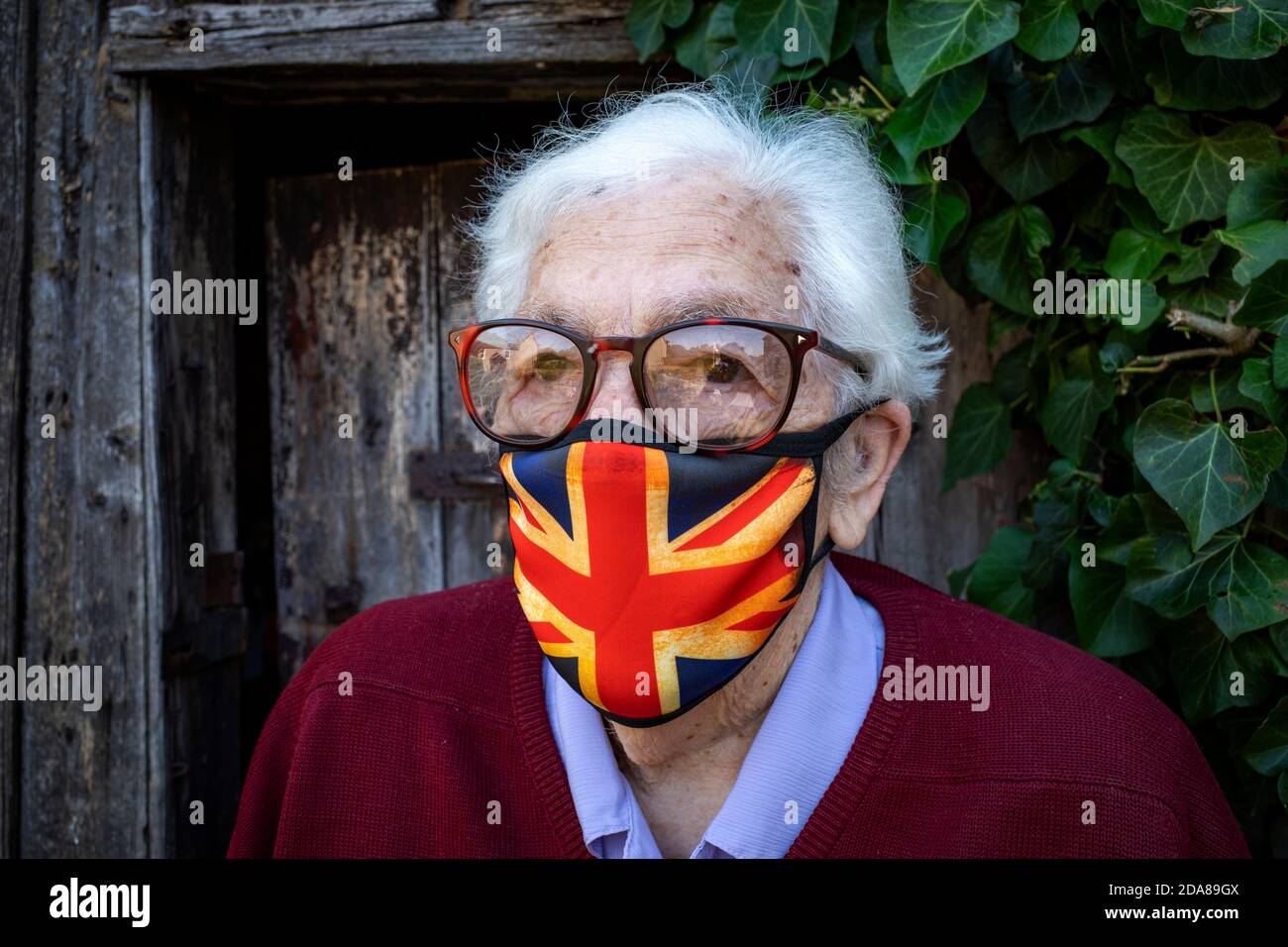 Rentnerin im Alter in ihrem Garten trägt einen Gesichtsausschanck Stockfoto