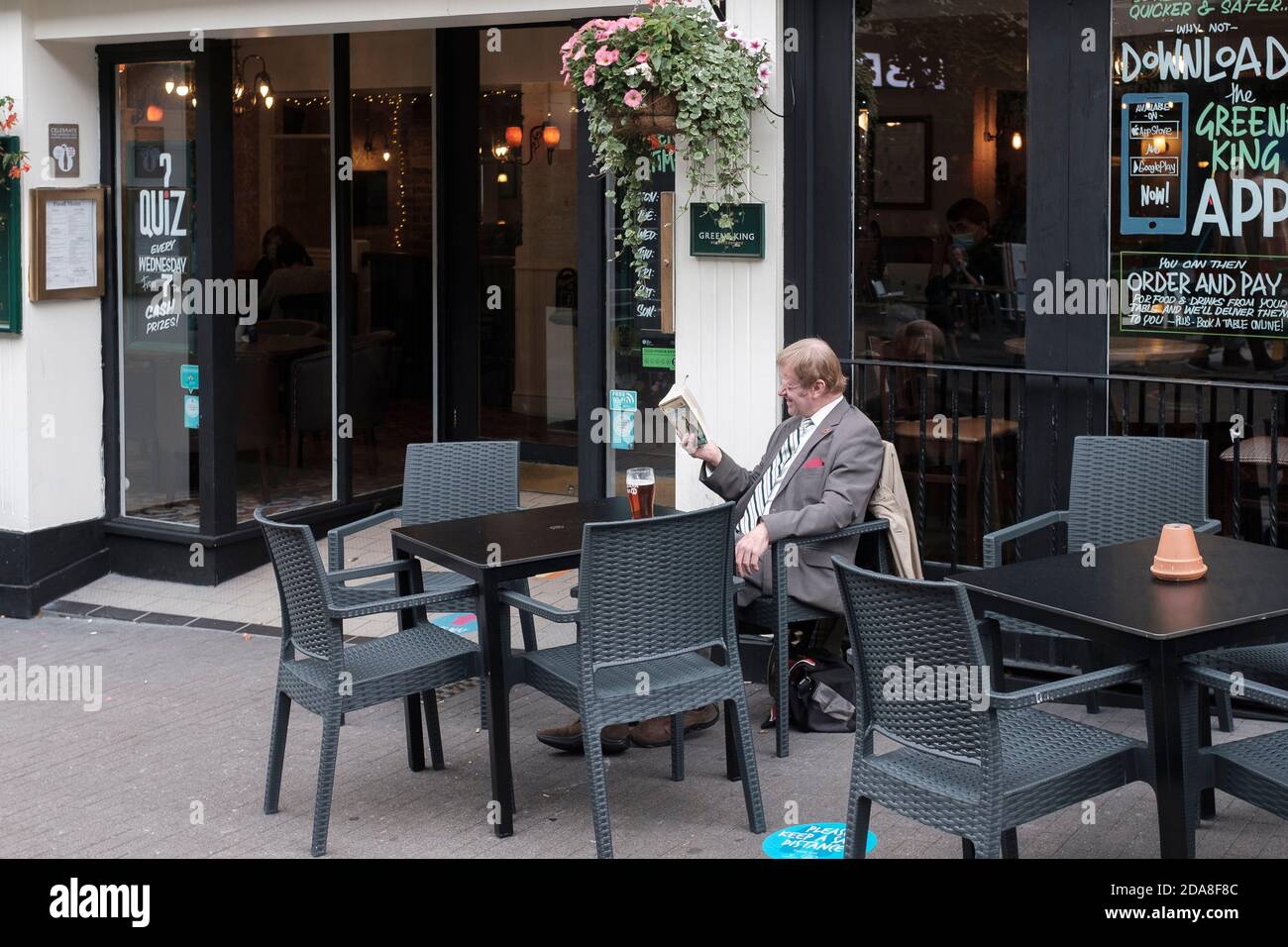 Mann liest ein Buch und genießt ein Pint draußen Pub, London, Großbritannien Stockfoto