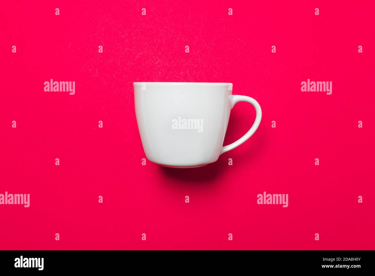 Eine weiße Kaffeetasse auf einem rosa einheitlichen Hintergrund mit weichem Licht und Schatten, als virtueller Hintergrund für Zoom-Meetings Stockfoto