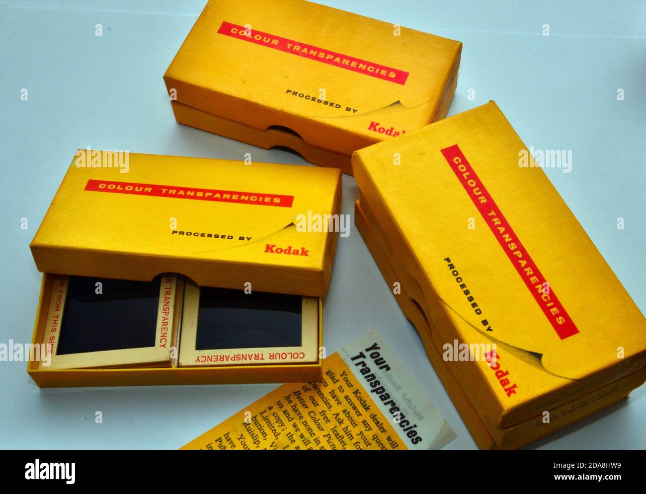Eine Studioaufnahme von alten Kodak 4 x 4 cm Dias in einer offenen Kodak Farbtransparenzbox mit ähnlichen Boxen daneben. Stockfoto