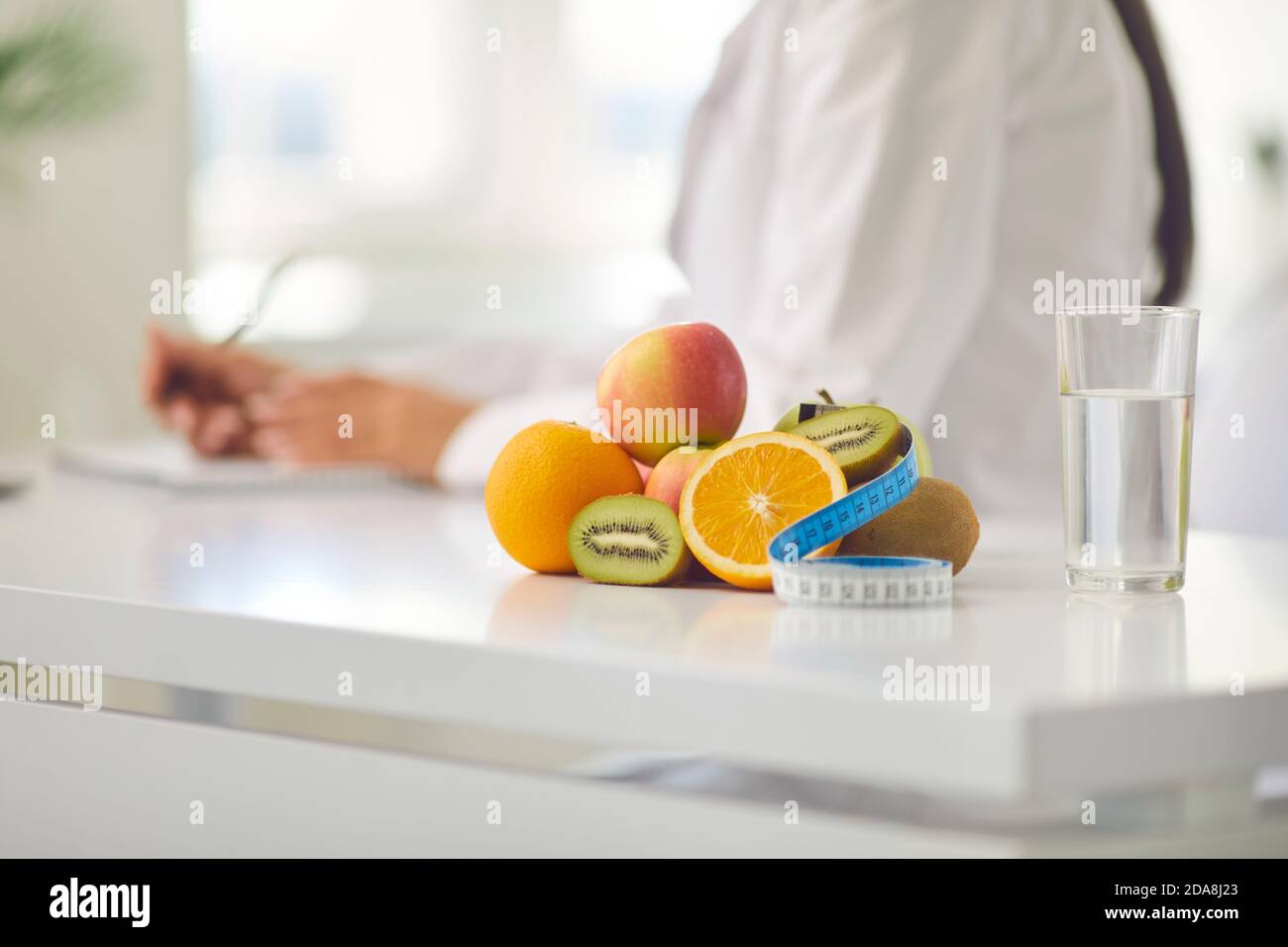 Frische reife Früchte, reines Trinkwasser und Maßband während der Online-Beratung Stockfoto
