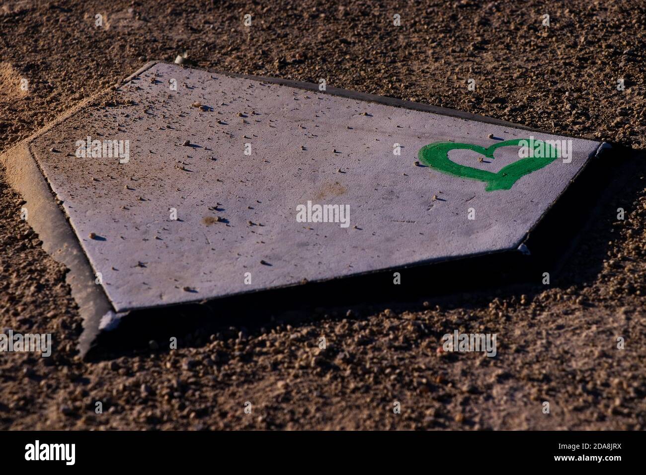 Grünes Herz an der Ecke der Heimplatte auf einem Softballfeld. Stockfoto