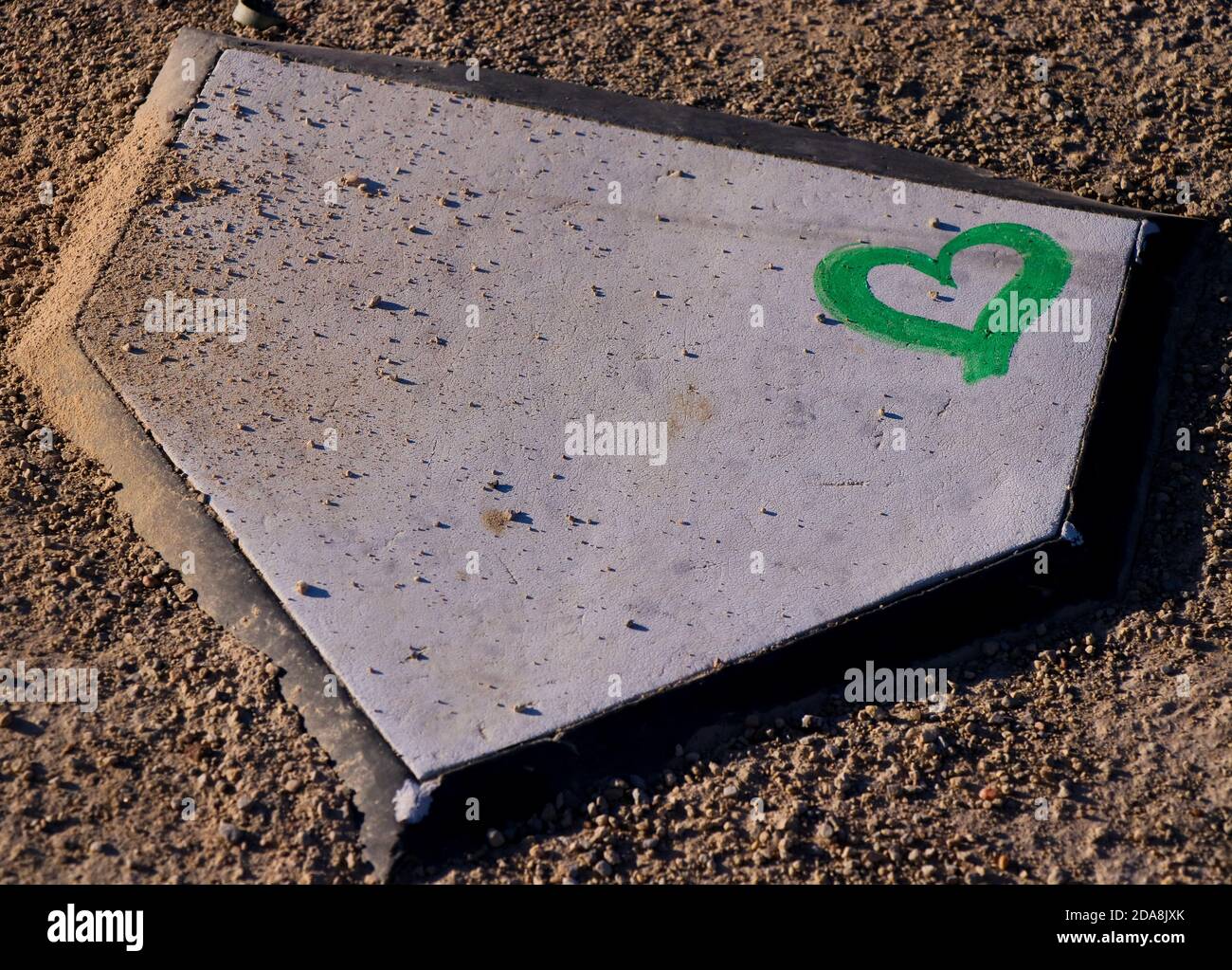 Grünes Herz an der Ecke der Heimplatte auf einem Softballfeld. Stockfoto