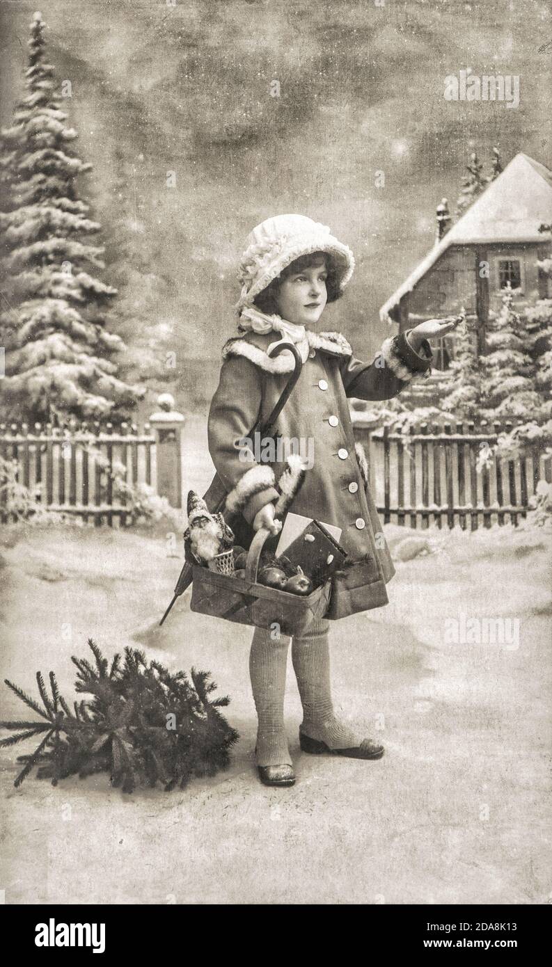 Kleines Mädchen mit weihnachtsbaum, Geschenke und Vintage-Spielzeug. Alte Postkarte mit Original-Film Maserung und Kratzern Stockfoto