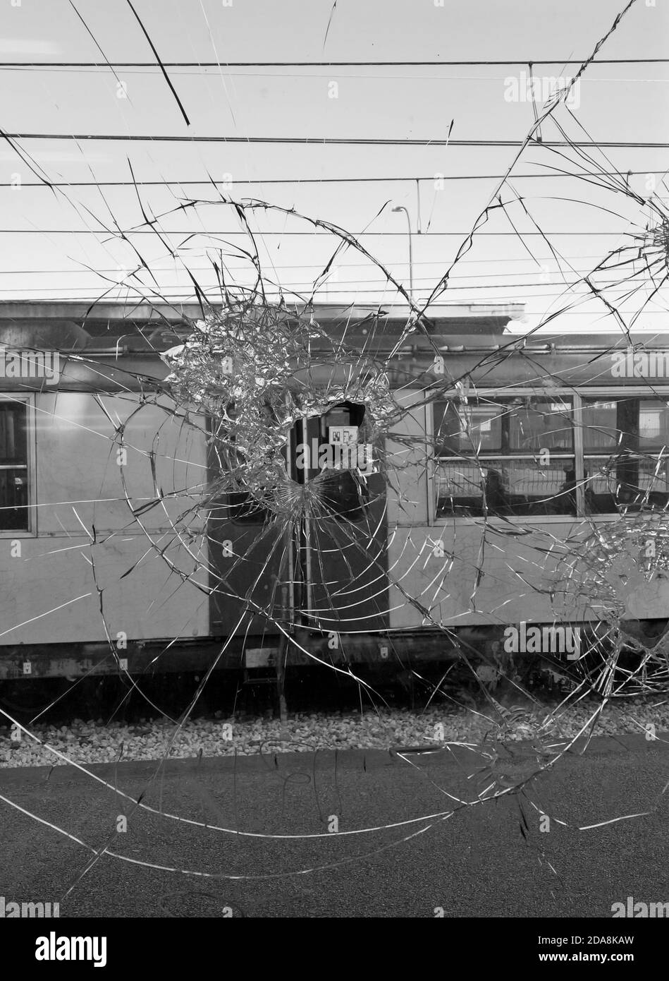 Blick auf einen Zug durch zerbrochenes Glas in einem Fenster In diesem Schwarz-Weiß-Foto, das in Süditalien aufgenommen wurde Stockfoto