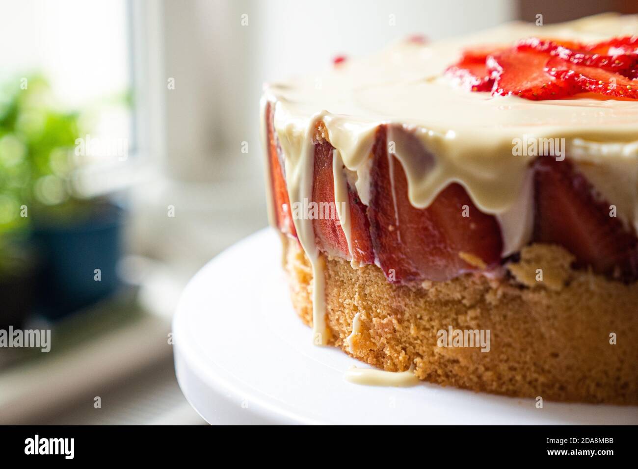 Kuchenseite mit weißer Sahne überlaufen. Geringe Schärfentiefe. Nahaufnahme. Stockfoto