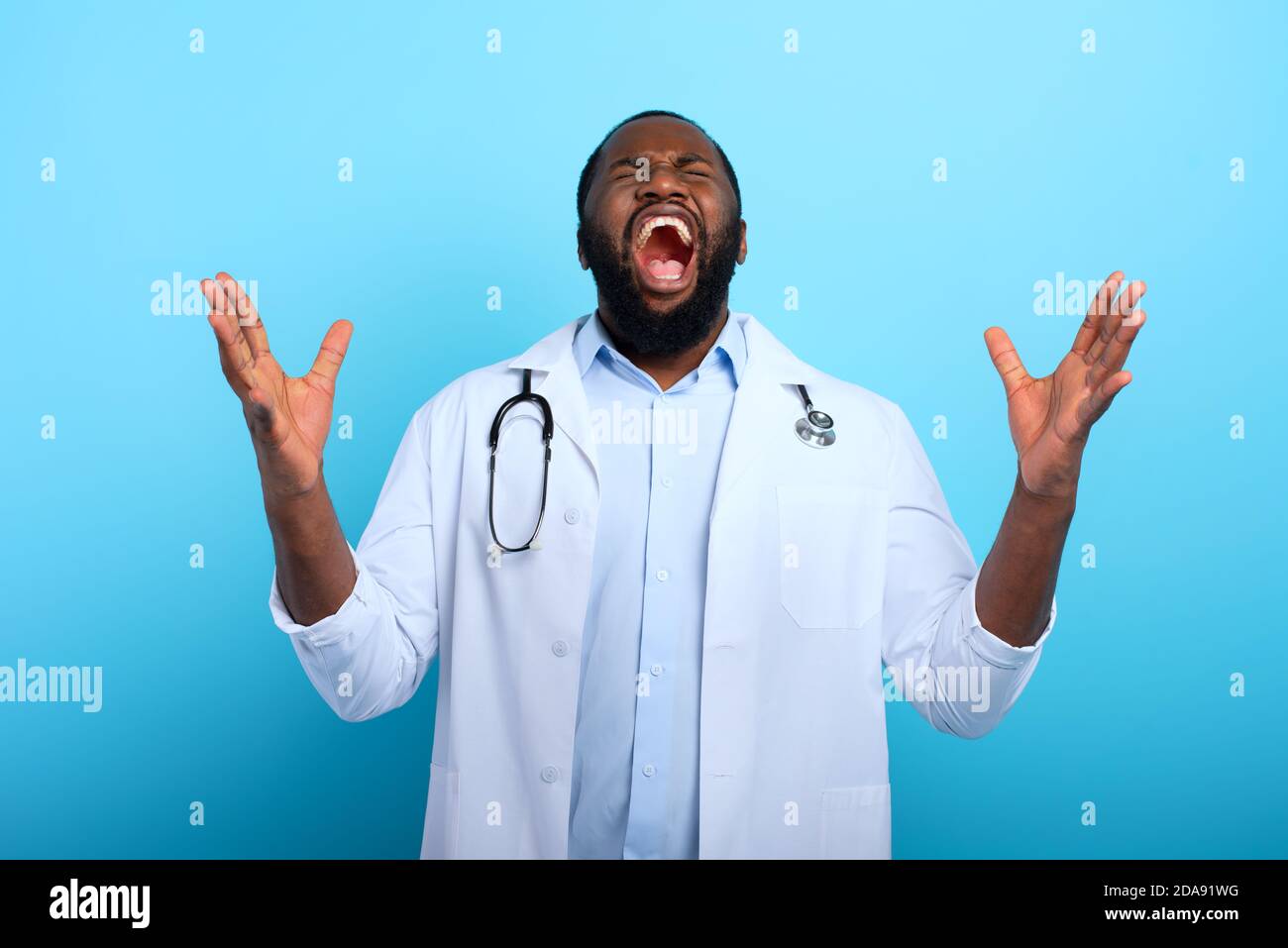 Arzt ist erschöpft und gestresst wegen Überlastung durch Coronavirus covid-19. Cyanfarbener Hintergrund Stockfoto