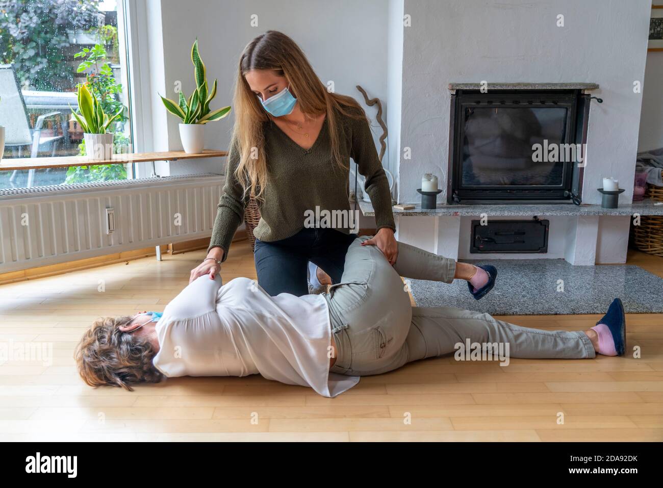 Erste Hilfe Massnahmen unter Corona-Bedingungen, stabile Seitenlage, nach einem Fall im der Wohnung, mit Mund-Nase-Maske, beim Ersthelfer Leistung Stockfoto