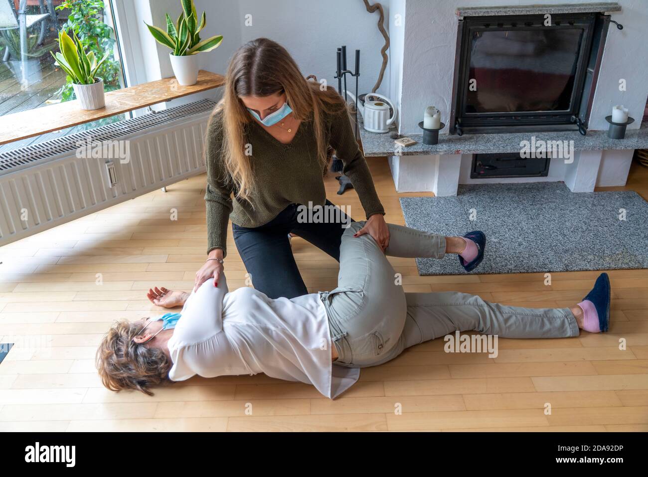 Erste Hilfe Massnahmen unter Corona-Bedingungen, stabile Seitenlage, nach einem Fall im der Wohnung, mit Mund-Nase-Maske, beim Ersthelfer Leistung Stockfoto