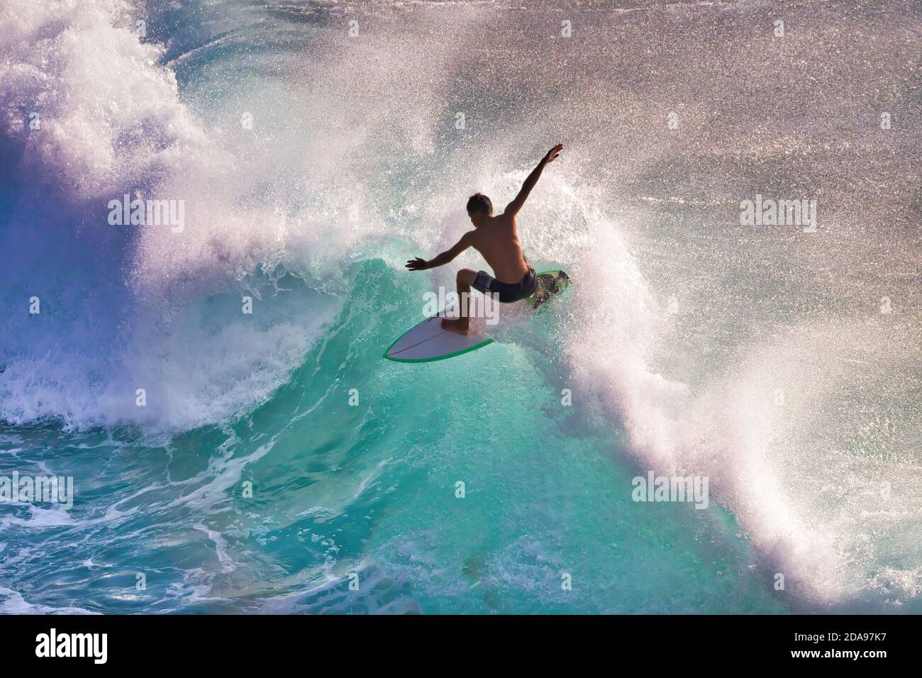 Actiongeladener Surfer in Silhouette auf einer hohen Energiewelle auf Maui. Stockfoto