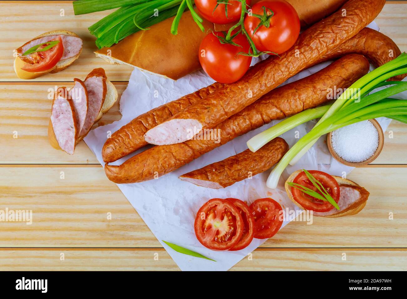 Tomaten, Brot und Kielbasa mit Schnittlauch auf Holzgrund. Nahaufnahme. Stockfoto