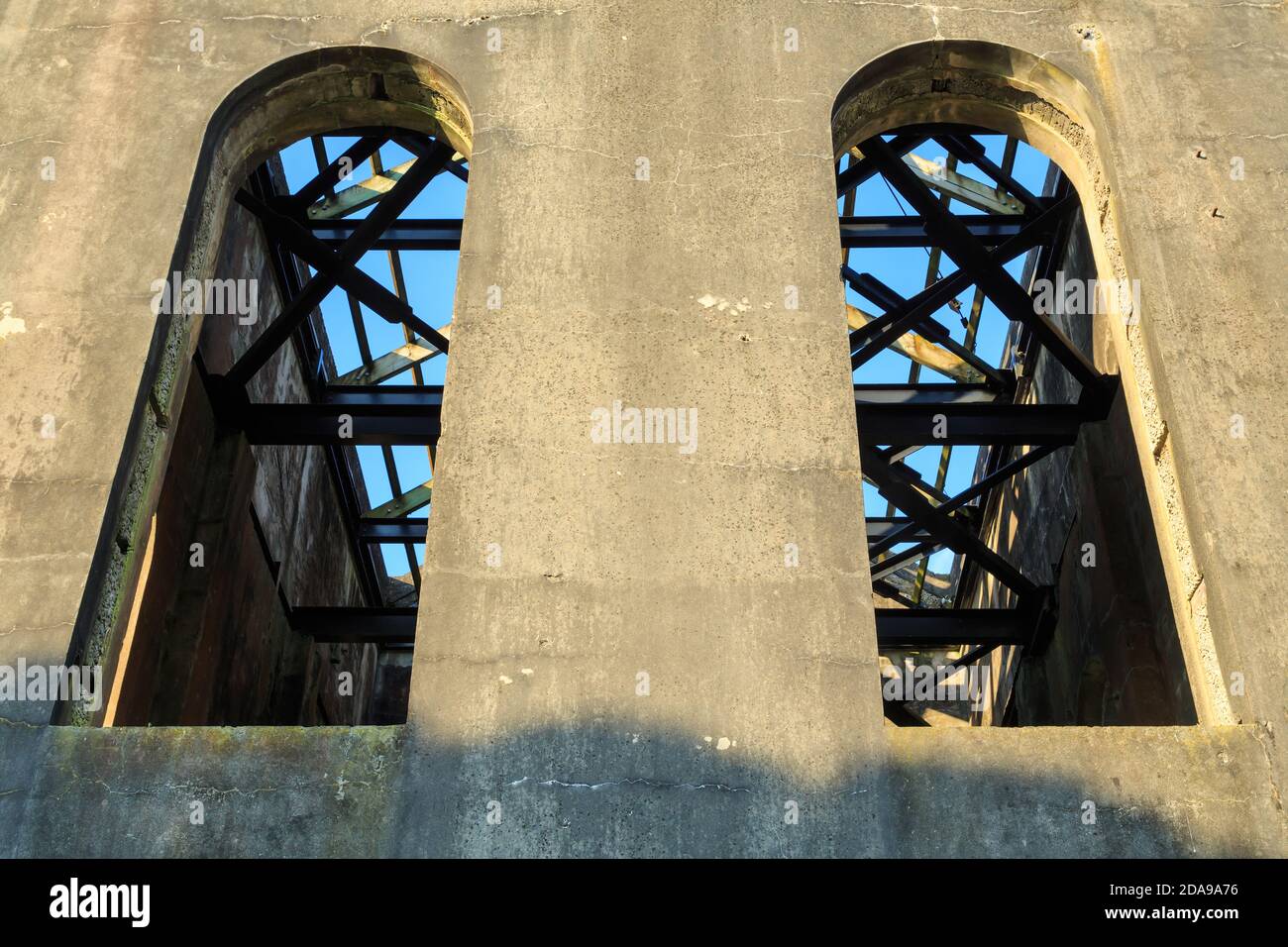 Die hohen, gewölbten Fenster und Metalldachbalken eines zerstörten Industriegebäudes, des alten Cornish Pumphouse in Waihi, Neuseeland Stockfoto