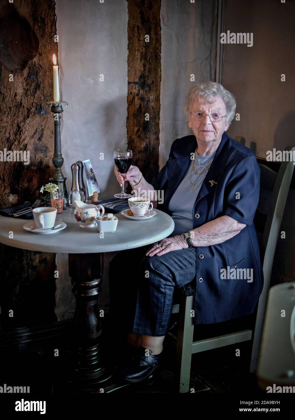 Die 90-jährige, nicht-agenarische englische Dame feiert ihren Geburtstag mit einem Glas Rotwein in einem Restaurant bei Kerzenschein. England, Großbritannien Stockfoto