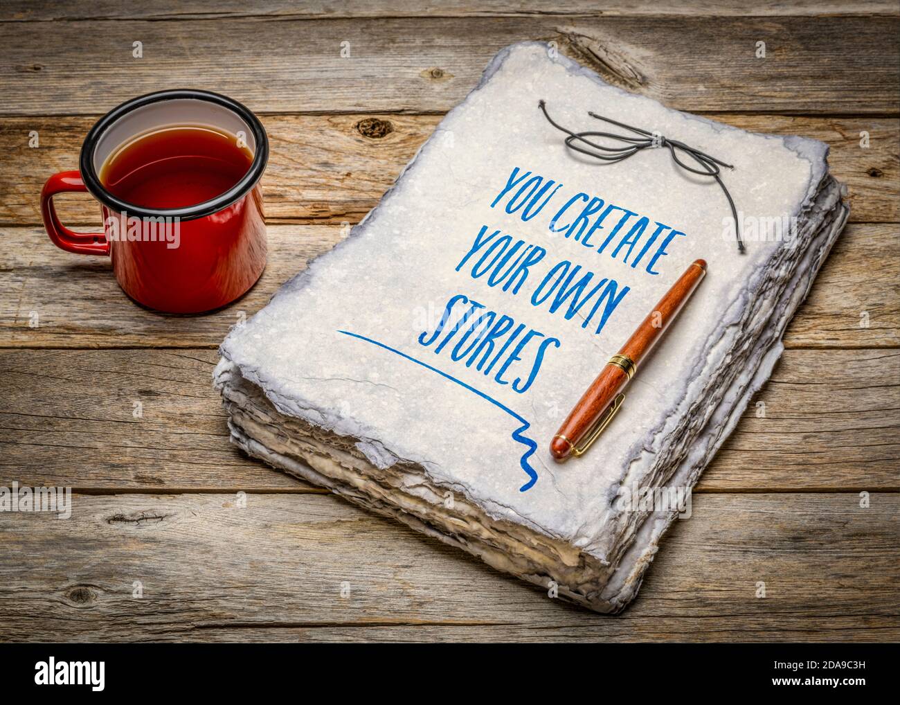 Sie erstellen Ihre eigenen Geschichten inspirierende Note - Handschrift in handgeschöpftem Papier Skizzenbuch mit Tasse Tee, Kreativität und persönliche Entwicklung concep Stockfoto