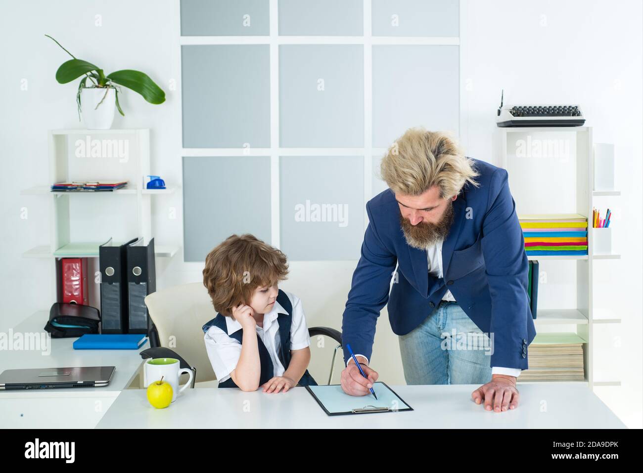 Kleines Kind, das auf einem Schreibtisch im Büro als Chef spielt. Marketing-Team Meeting Brainstorming Forschung. Stockfoto