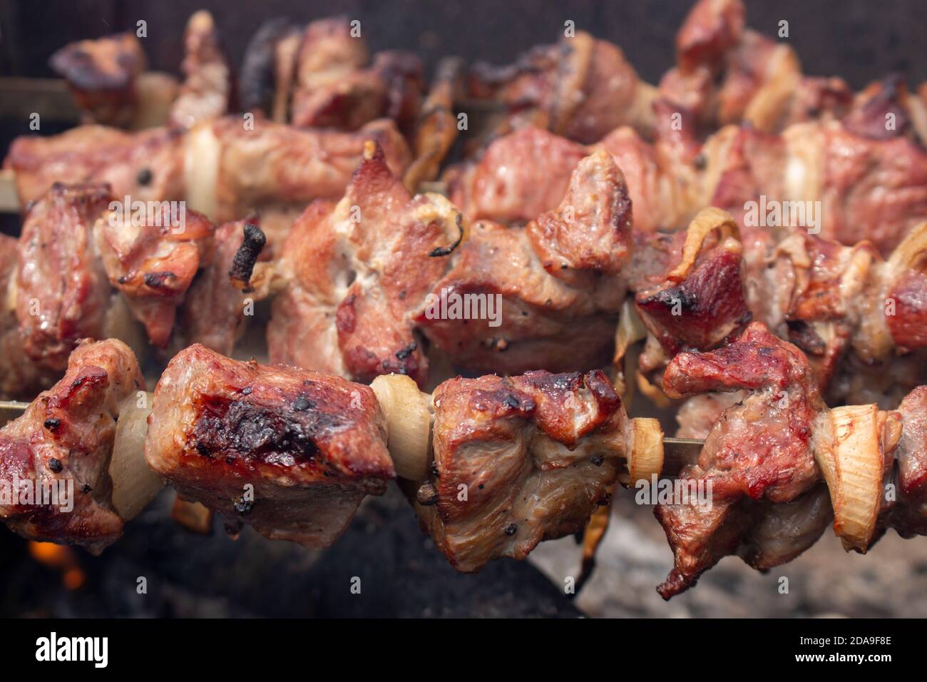 Geröstete Fleischstücke zum Rauchen im Grill, Braten Grill mit Freunden oder Familie im Urlaub. Das Schweinefleisch wird auf Feuer gebraten. Stockfoto