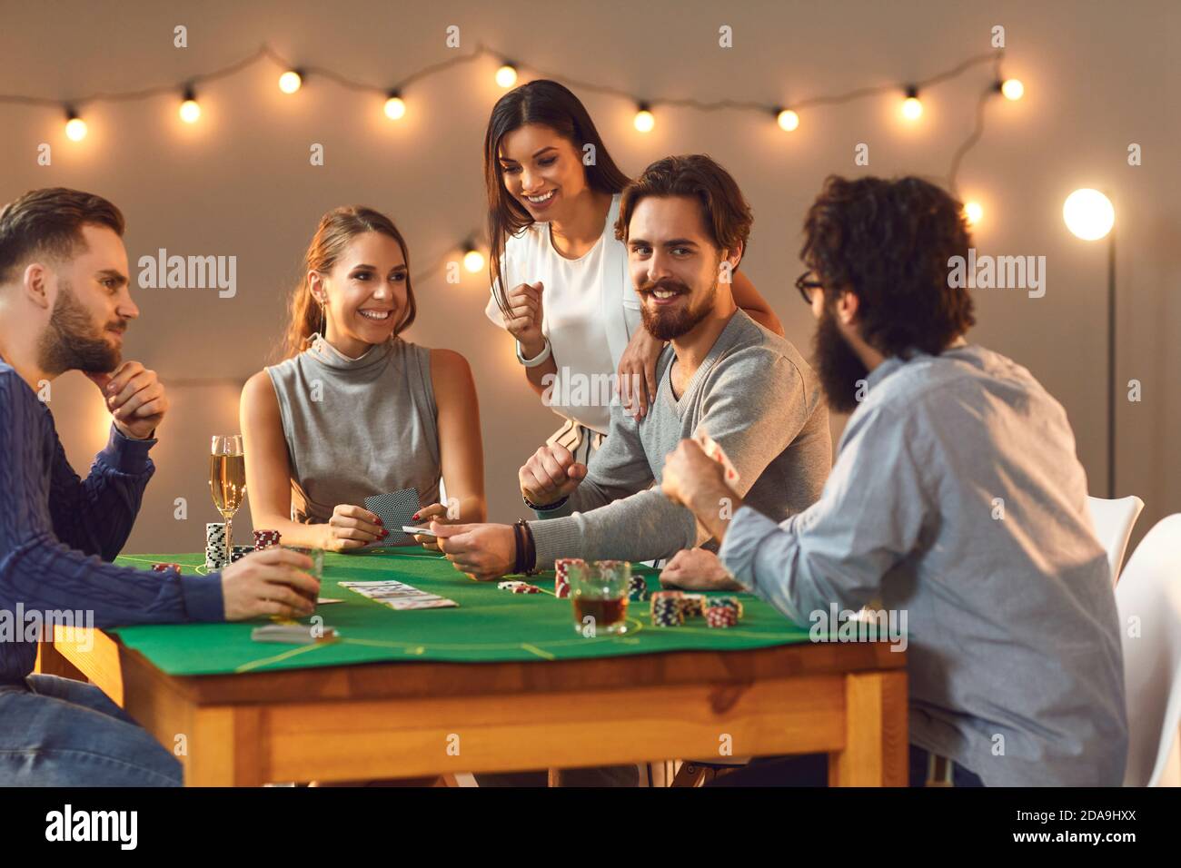 Glückliche Freunde wetten, spielen Poker spielen am Tisch mit Getränken zu Hause Stockfoto