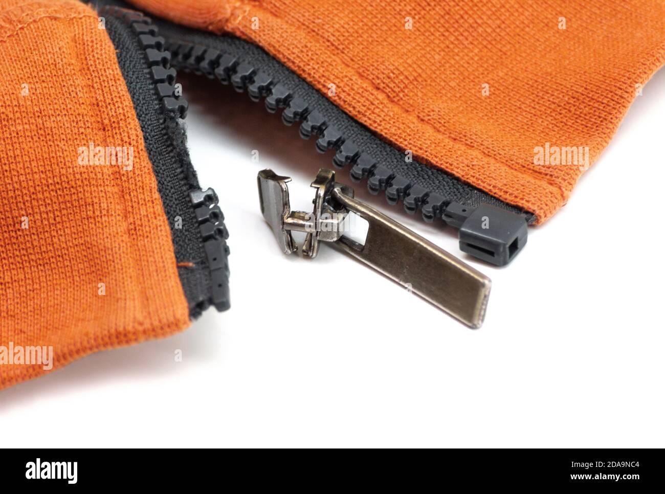 Gebrochener Reißverschluss an orangefarbener Hemdjacke. Detailfoto in Nahaufnahme. Reparaturkonzept für Kleidung Stockfoto