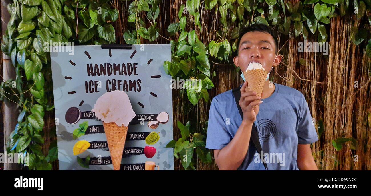 Junger asiatischer Mann genießt es, handgemachte Eiscreme zu essen Stockfoto