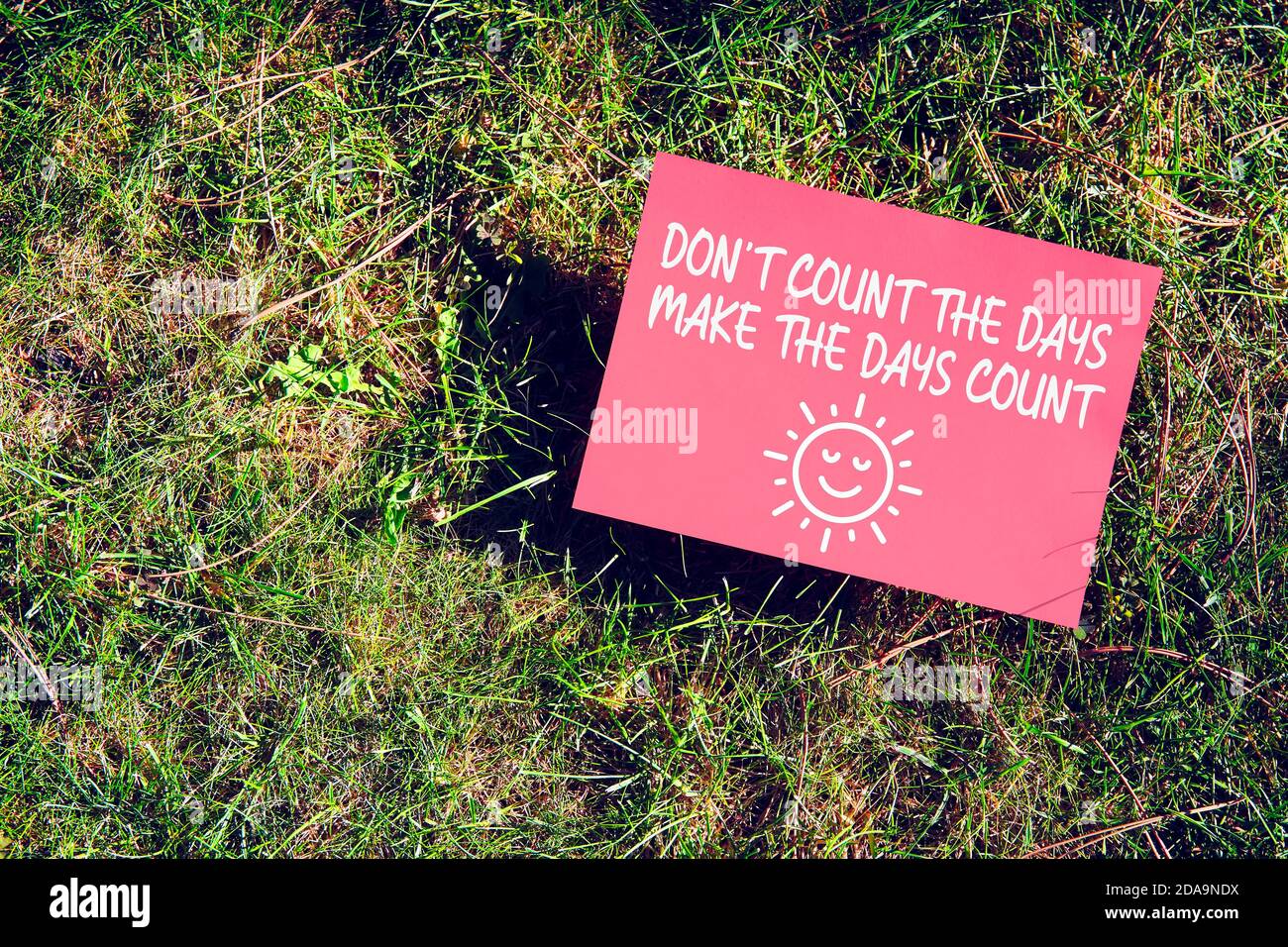 Inspirierende Botschaft von Zählen Sie nicht die Tage, lassen Sie die Tage zählen auf dem Papier auf grünem Gras in der Natur. Produktiv zu sein und das Beste aus dem Leben zu machen Stockfoto