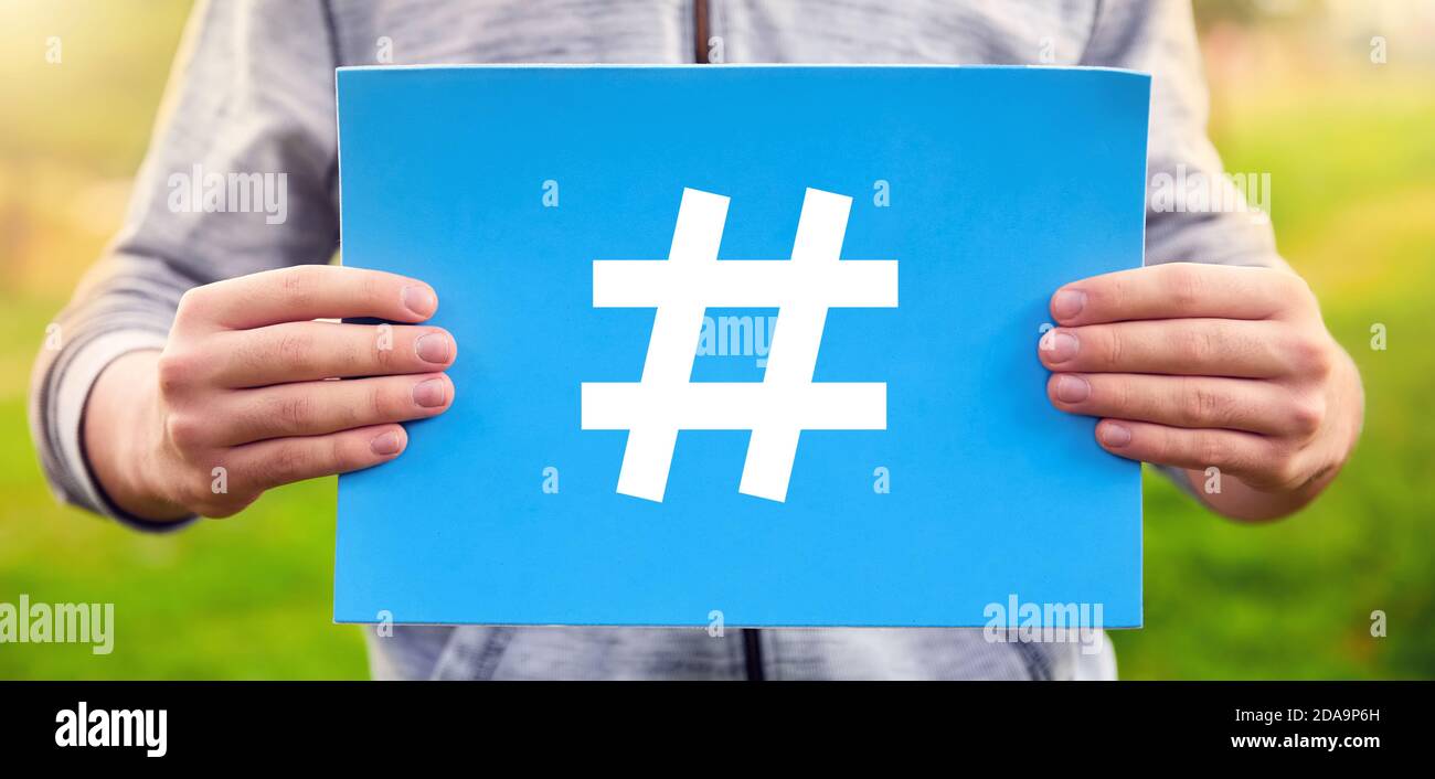 Männlicher Teenager hält ein blaues Banner mit Hashtag-Symbol vor dem  Hintergrund der Natur. Social Media Kommunikationskonzept Stockfotografie -  Alamy