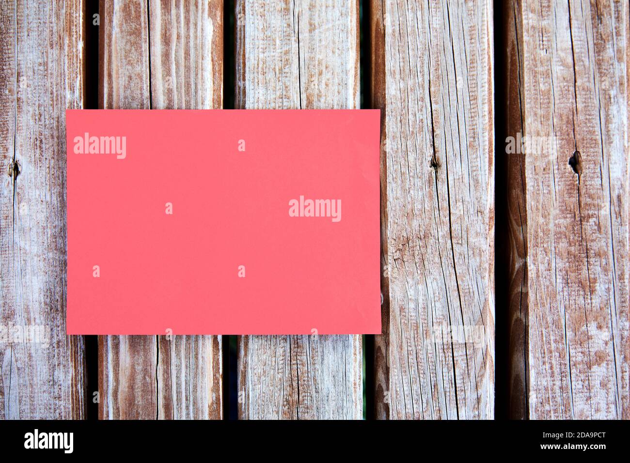 Leeres rotes Papierschild oder eine Notiz, die auf einem Holztisch im Freien aufgemockt wird. Stockfoto