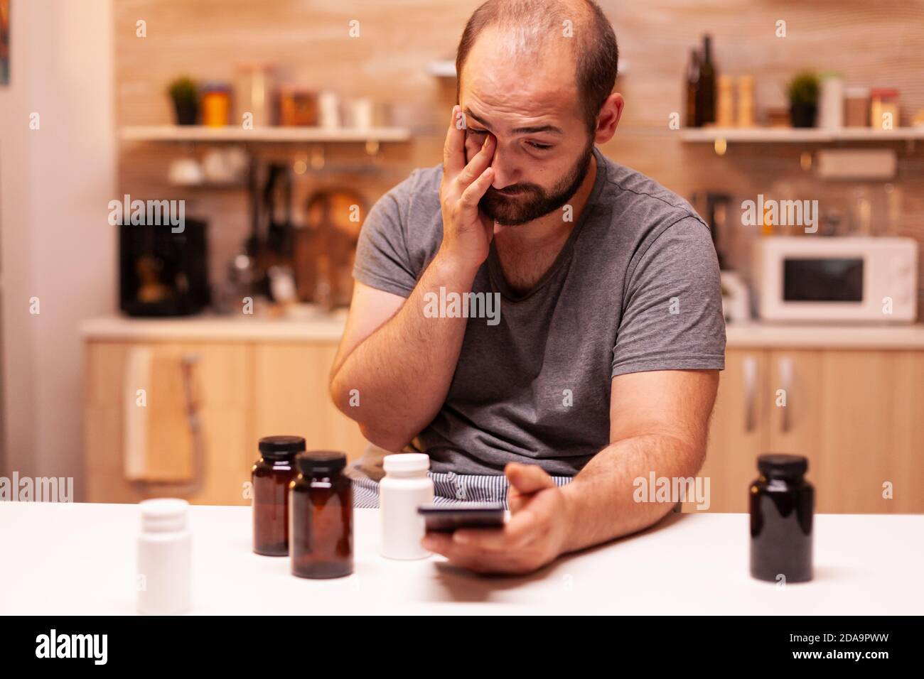 Mann mit Schmerzen sucht am Telefon medizinische Behandlung. Gestresst müde unglücklich besorgt unwohl Person leiden an Migräne, Depression, Krankheit und Angst Gefühl erschöpft mit Schwindelsymptomen Stockfoto