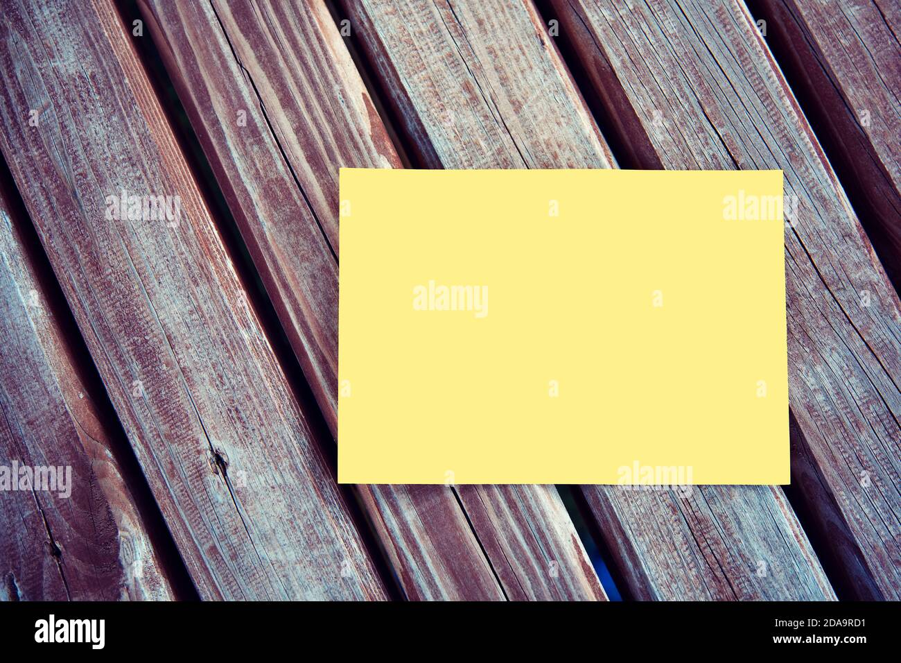 Leeres, gelbes Papier auf einem Holztisch im Freien. Stockfoto