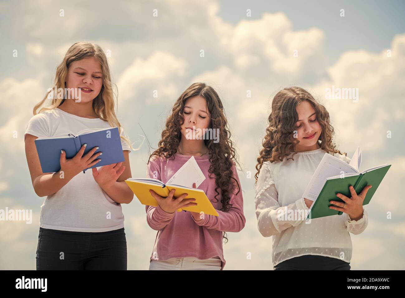 Bildung und Schulkonzept. Schüler lernen Literatur. Kinder lesen Bücher. Drei Mädchen schreiben in Notebook. Zurück zur Schule. Schreiben Erinnerungen in Tagebuch. Stockfoto