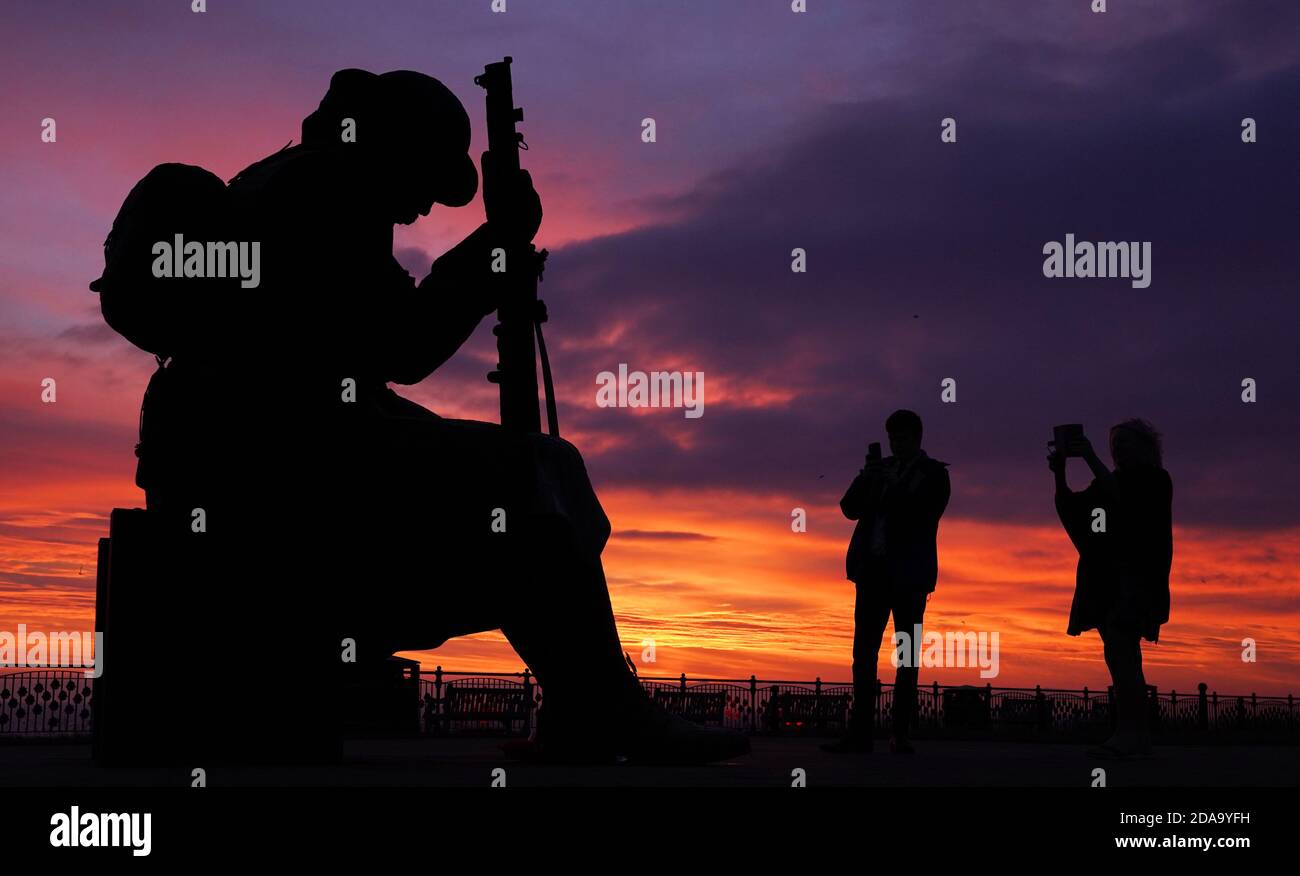 Am Jahrestag des Waffenstillstands-Tages gehen die Menschen an der Tommy-Statue, offiziell 1101 genannt, auf Terrace Green an der Strandpromenade in Seaham, County Durham, vorbei. Stockfoto