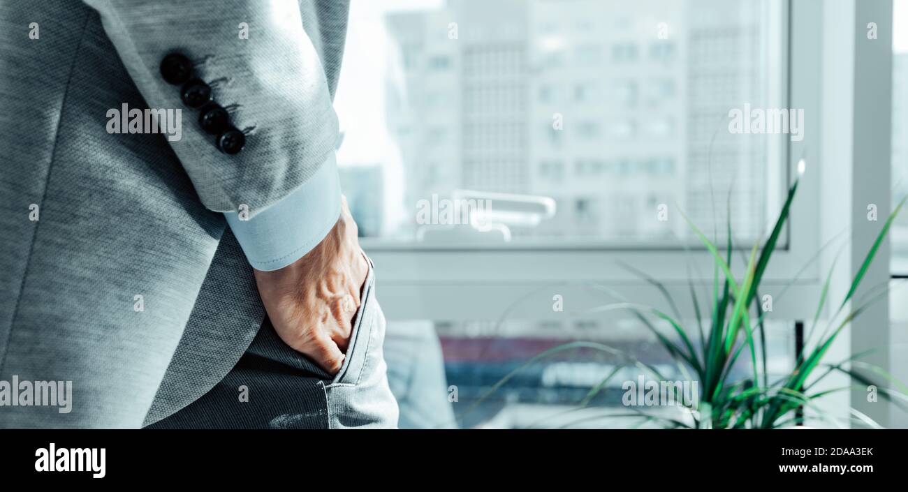 Mann Hand in seiner Hosentasche. Grauer Business-Anzug. Männlich in der Nähe des Bürofensters Stockfoto