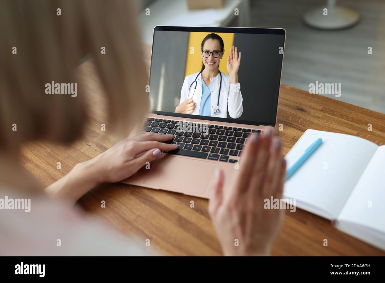 Ärztin auf Laptop-Bildschirm winkt Hand zu kranken Patienten Stockfoto