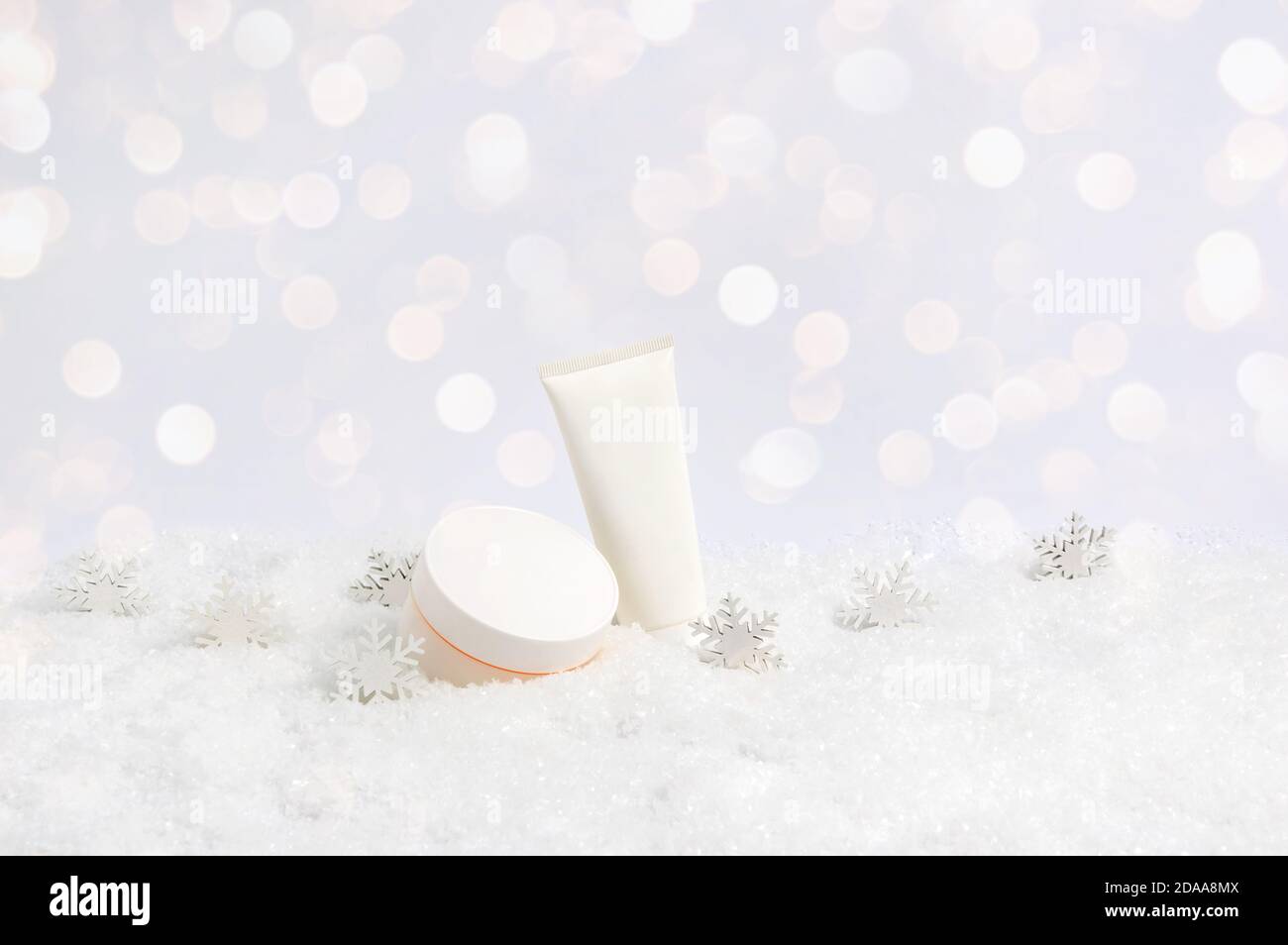 Set von Winter Hautpflege Kosmetik-Produkte in Schnee und Schneeflocken auf weißem Hintergrund mit Bokeh Lichter. Gesichtscreme und Handcreme oder Körperlotion Stockfoto