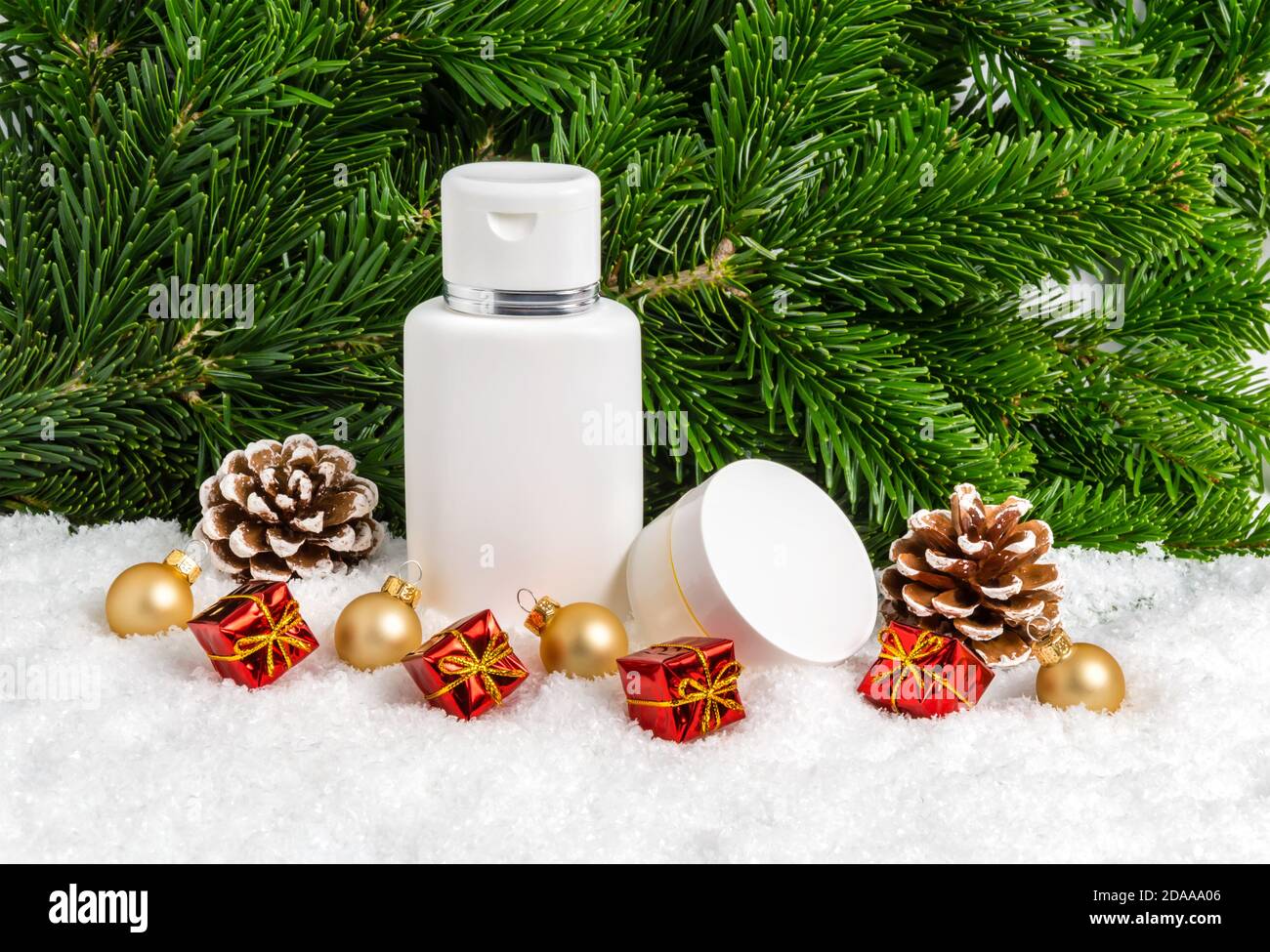 Set von Winter Hautpflege Kosmetik-Produkte im Schnee unter Weihnachtsbaum mit Geschenken, Tannenzapfen und Kugeln. Gesichtscreme Glas und Bodylotion Flasche Stockfoto