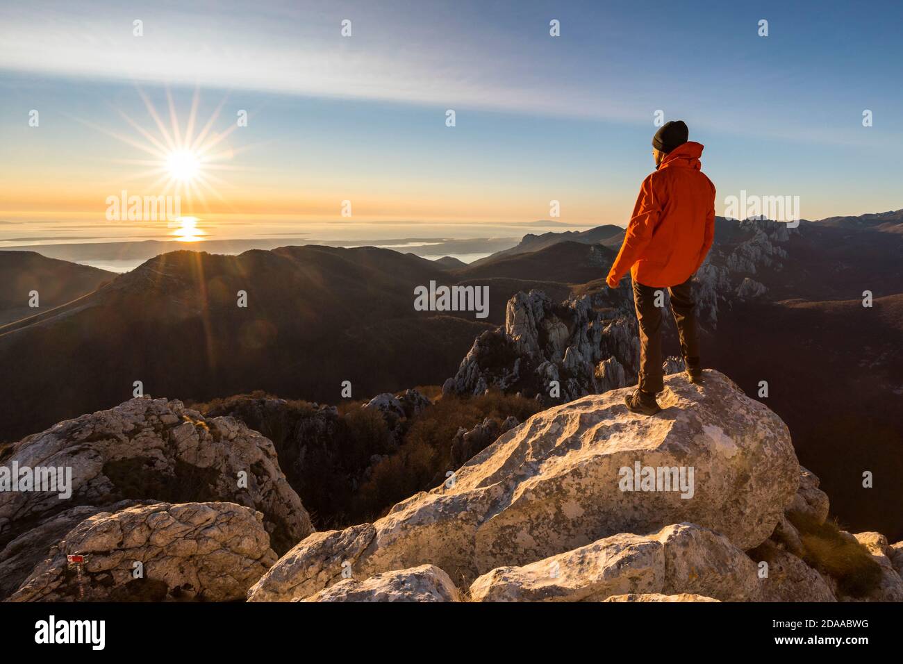 Kletterer steht auf der Bergspitze und wachende Sonnenuntergang Stockfoto