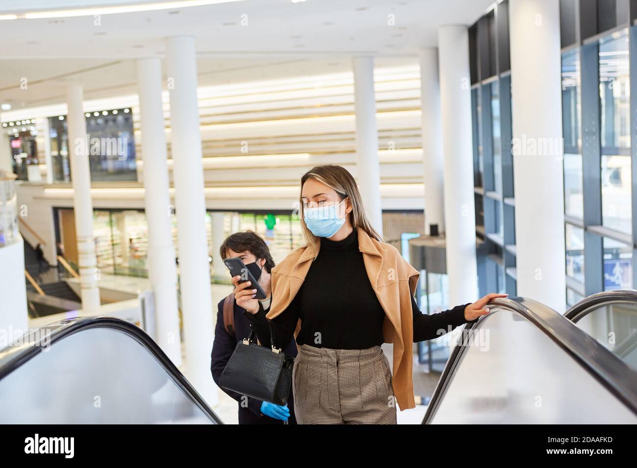Geschäftsfrau mit Maske wegen Covid-19 schaut auf Smartphone Mit Warnung App Stockfoto