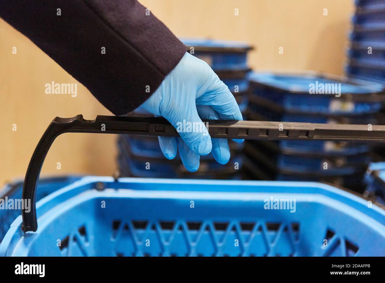 Hand in Latexhandschuhe mit Einkaufskorb im Supermarkt Wegen der Covid-19-Pandemie Stockfoto