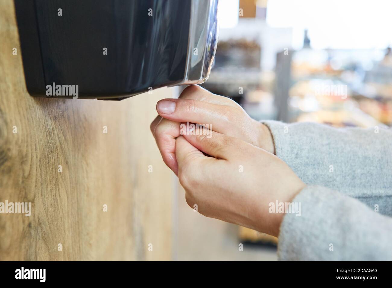 Kunde am Desinfektionsmittelspender am Eingang Supermarkt fällig Zur Pandemie Covid-19 Stockfoto