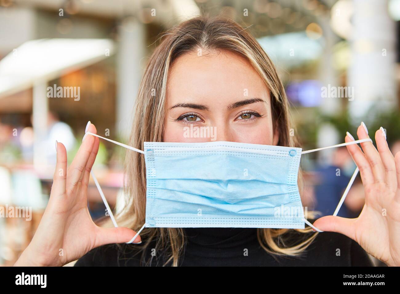 Frau hält Maske oder Mundschutz mit beiden Händen als Anleitung Zum Schutz vor Infektionen Stockfoto