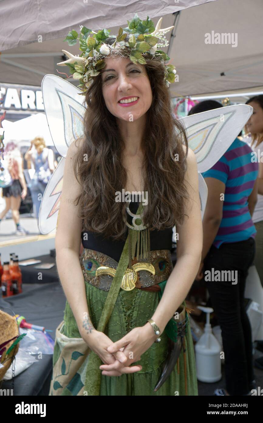 Posed Porträt eines Verkäufers auf Witchsfest trägt einen Kranz und Schmetterling Flügel.. In Greenwich Village, New York City. Stockfoto