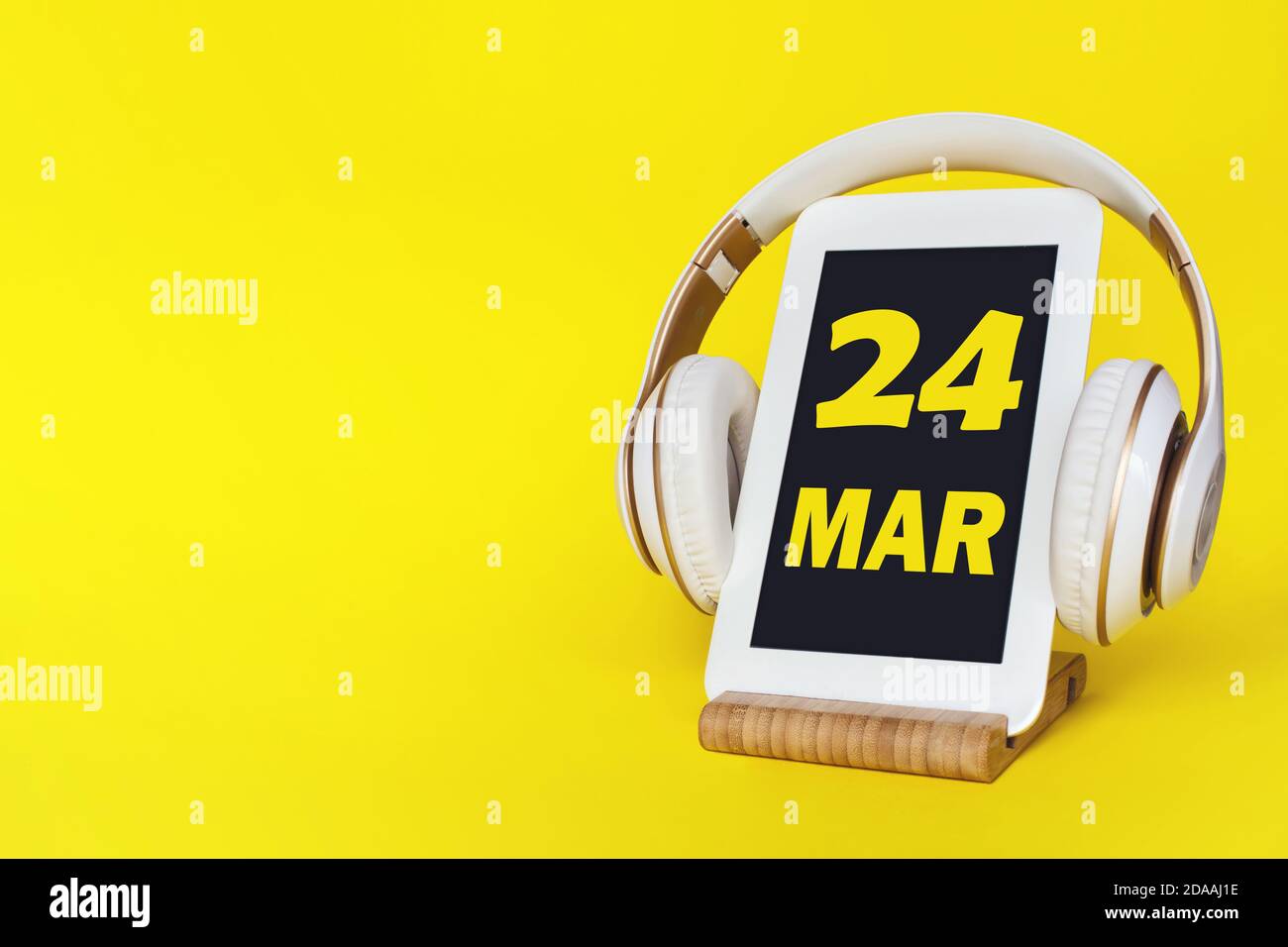 März. Tag 24 des Monats, Kalenderdatum. Elegante Kopfhörer und modernes Tablet auf gelbem Hintergrund. Leerzeichen für Text. Konzept Bildung, Technologie, Stockfoto