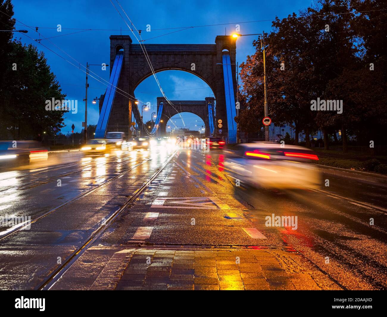 Regnerische Stadtstraße in der Nacht, nächtlicher Verkehr auf nasser Straße bei Regen, Straßenbeleuchtung in Pfützen reflektiert. Stockfoto