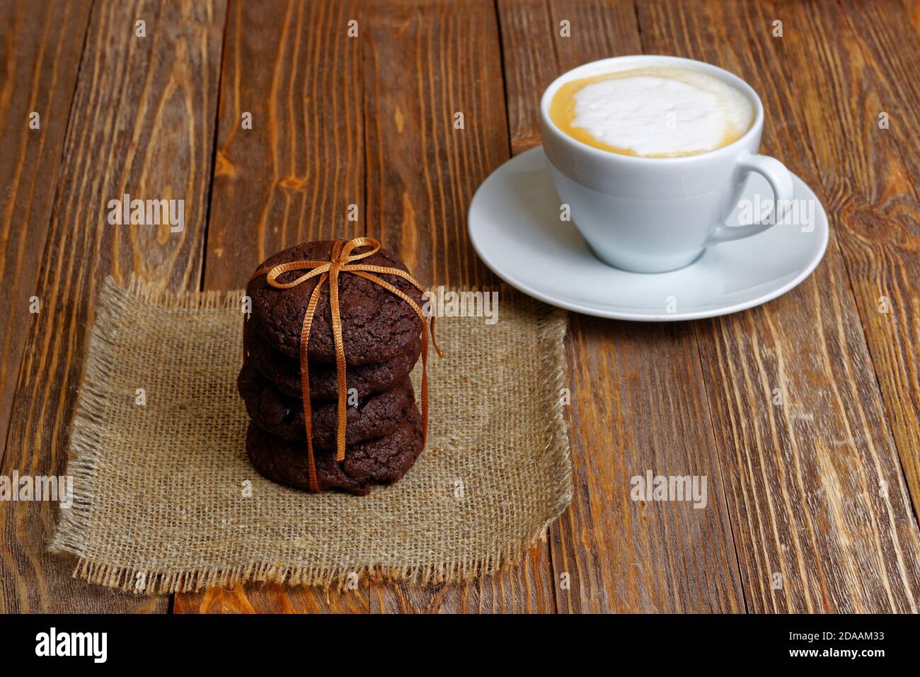 Stapel Schokoladenkekse und Tasse Kaffee auf Holztisch. Stockfoto